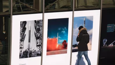 Une personne devant trois grandes photos dans une gare