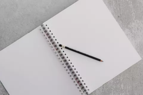 Un carnet vierge avec un crayon sur une surface en béton