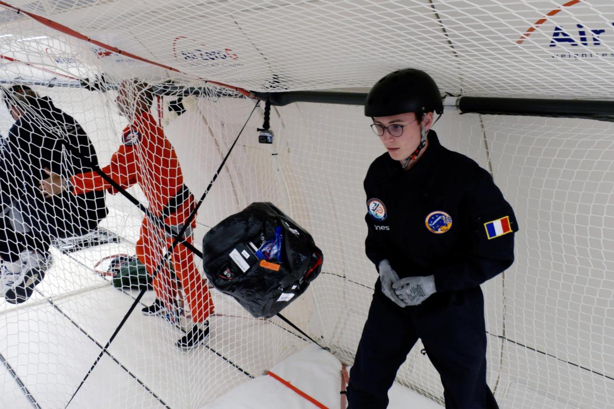 Etudiant devant un drone à air comprimé flottant en micropesanteur. 